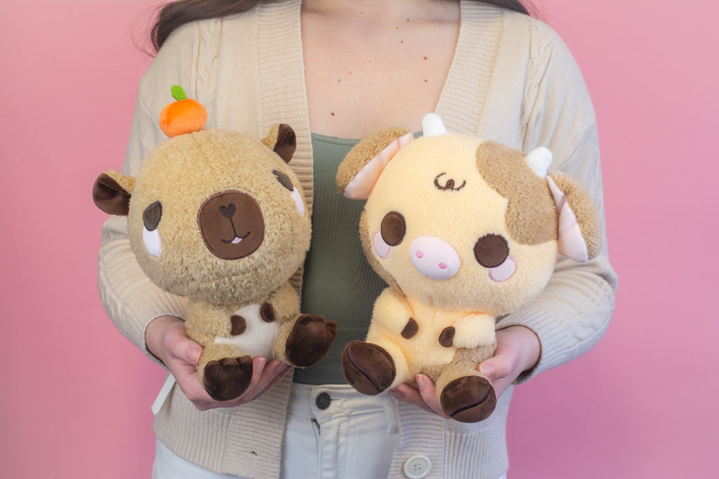 Person holding a capybara and coffee cow plushie